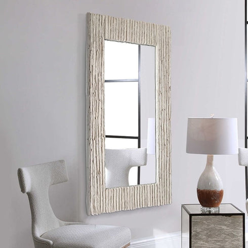 Rectangular grey mirror adding depth to a modern bedroom