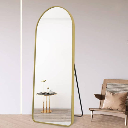 Freestanding arched mirror with gold aluminium frame reflecting room light