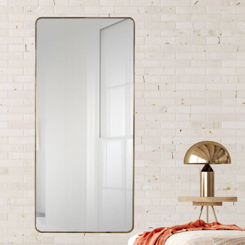 Tall gold wall mirror reflecting natural light in modern living space