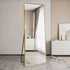 Tall gold mirror reflecting light in a modern living room setting