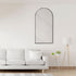 Arched wall mirror with black frame styled above a sofa in a living room