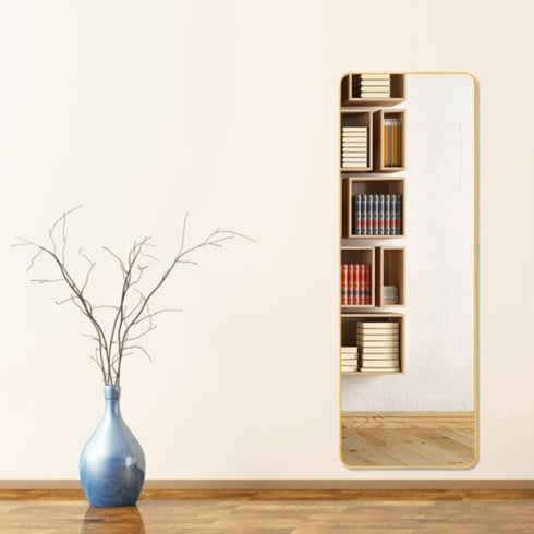Caelan gold full-length mirror with rounded edges hung on a wall
