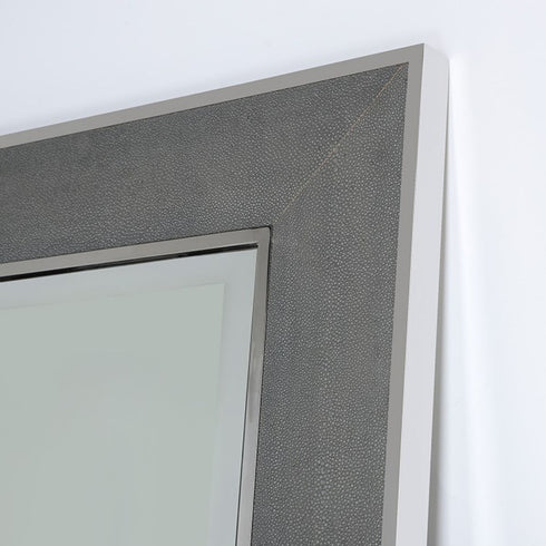 Edge detail of tall wall mirror with stainless steel finish and grey leather accents