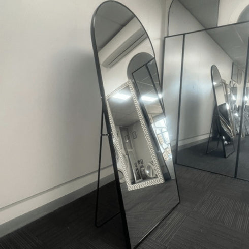 Side view of an arched black aluminium floor mirror with sturdy back support