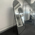 Side view of an arched black aluminium floor mirror with sturdy back support