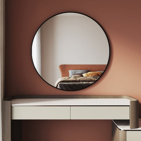 80cm round black wall mirror with powder-coated aluminum frame mounted above a bedroom dresser