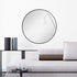 Round black wall mirror reflecting natural light in living room