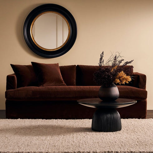 Black and brass Cecille Round Mirror hung above sofa in living room